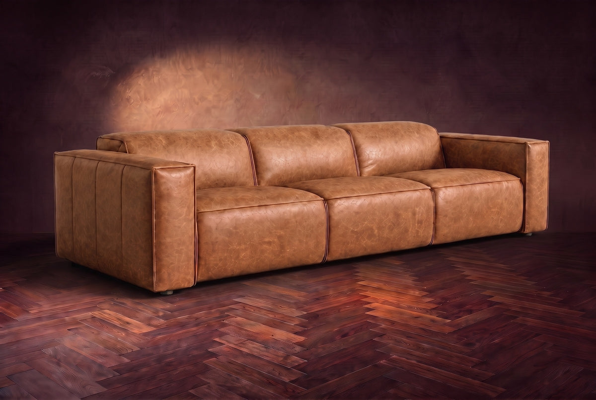The Emery 3 seat in Tuscan Cognac distressed full leather on a dark herringbone floor, headrests down and footrests closed. Shown in Tuscan Cognac, 3 seat.
