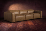 The Emery 3 seat in Weathered Saddle distressed full leather on a dark herringbone floor, headrests down and footrests closed. Shown in Weathered Saddle, 3 seat.