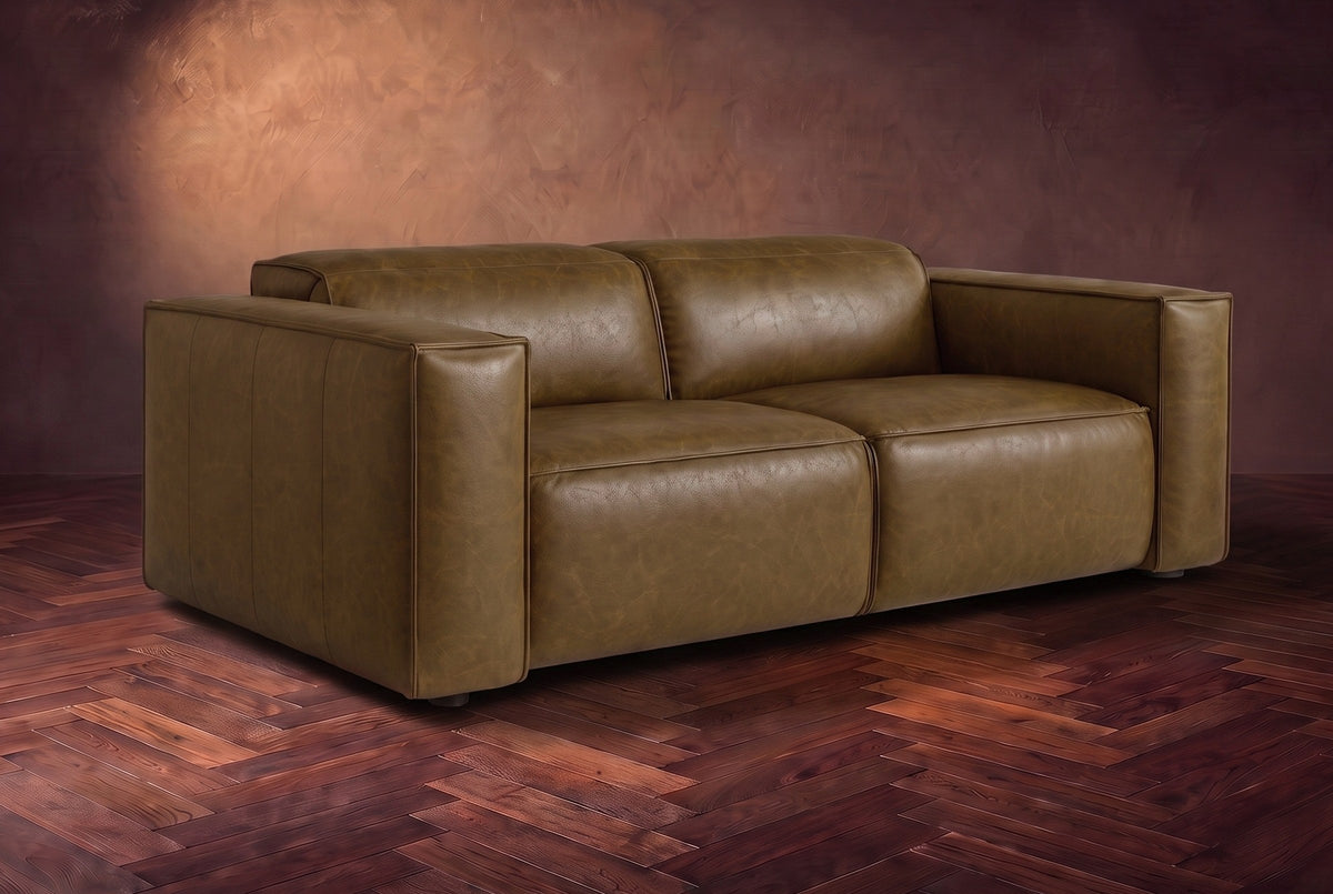 The Emery loveseat in Weathered Saddle distressed full leather on a dark herringbone floor, headrests down and footrests closed. Shown in Weathered Saddle, Loveseat.