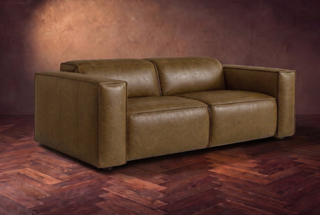 The Emery loveseat in Weathered Saddle distressed full leather on a dark herringbone floor, headrests down and footrests closed. Shown in Weathered Saddle, Loveseat.