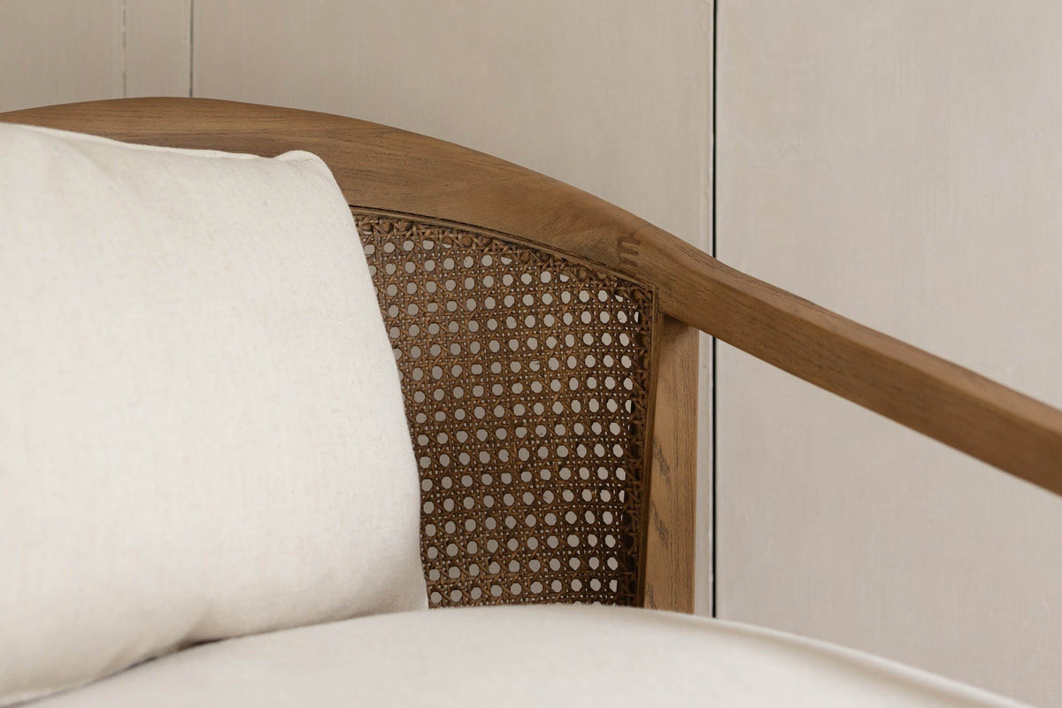 Close-up of the Esanatoglia ash band curving over the open cane back, the Sand Boucle back pillow and seat beside it