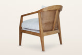 Esanatoglia accent chair from the rear three-quarter on a warm white studio backdrop: the curved open cane back with one cent