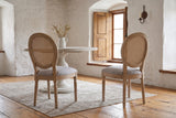 Two Este dining chairs seen from behind in a whitewashed stone dining room in Quebec City with a pine floor
