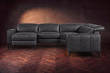 The Esther sectional seen from the front in Aged Slate distressed full leather on a dark herringbone floor, the chaise facing the camera and the footrest closed. Shown in Aged Slate, Left chaise.