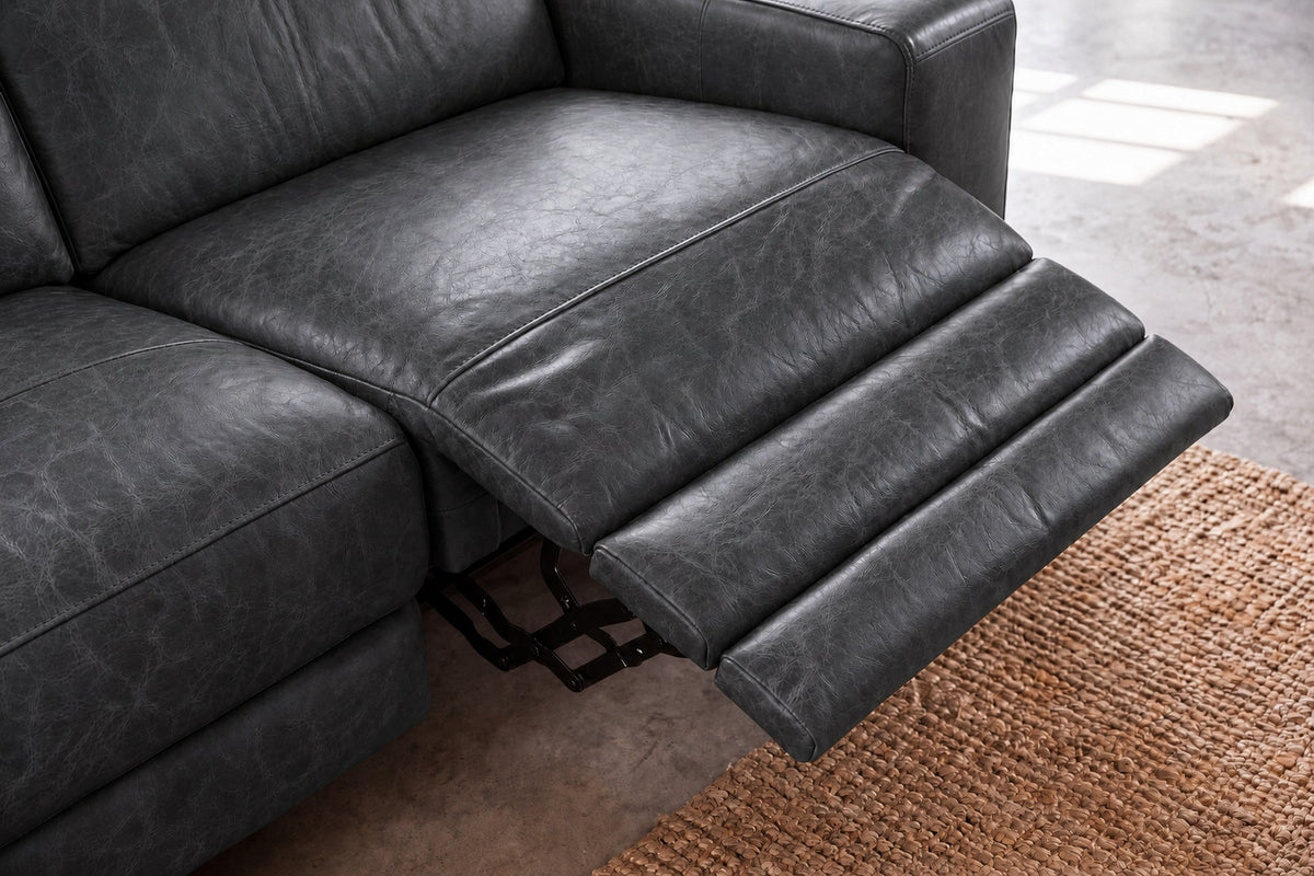 Looking down on the open Esther recliner in Aged Slate: the one-piece footrest out in three padded stages over a jute rug, the seat beside it closed. Shown in Aged Slate, Left chaise.