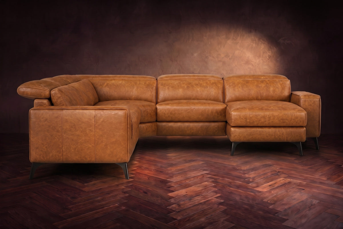 The Esther sectional seen from the front in Antiqued Caramel distressed full leather on a dark herringbone floor, the chaise facing the camera and the footrest closed. Shown in Antiqued Caramel, Right chaise.