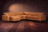 The Esther sectional in Antiqued Caramel distressed full leather on a dark herringbone floor, headrests down and footrest closed. Shown in Antiqued Caramel, Left chaise.