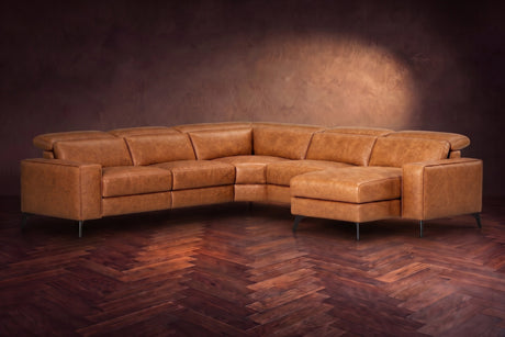 The Esther sectional in Antiqued Caramel distressed full leather on a dark herringbone floor, headrests down and footrest closed. Shown in Antiqued Caramel, Right chaise.
