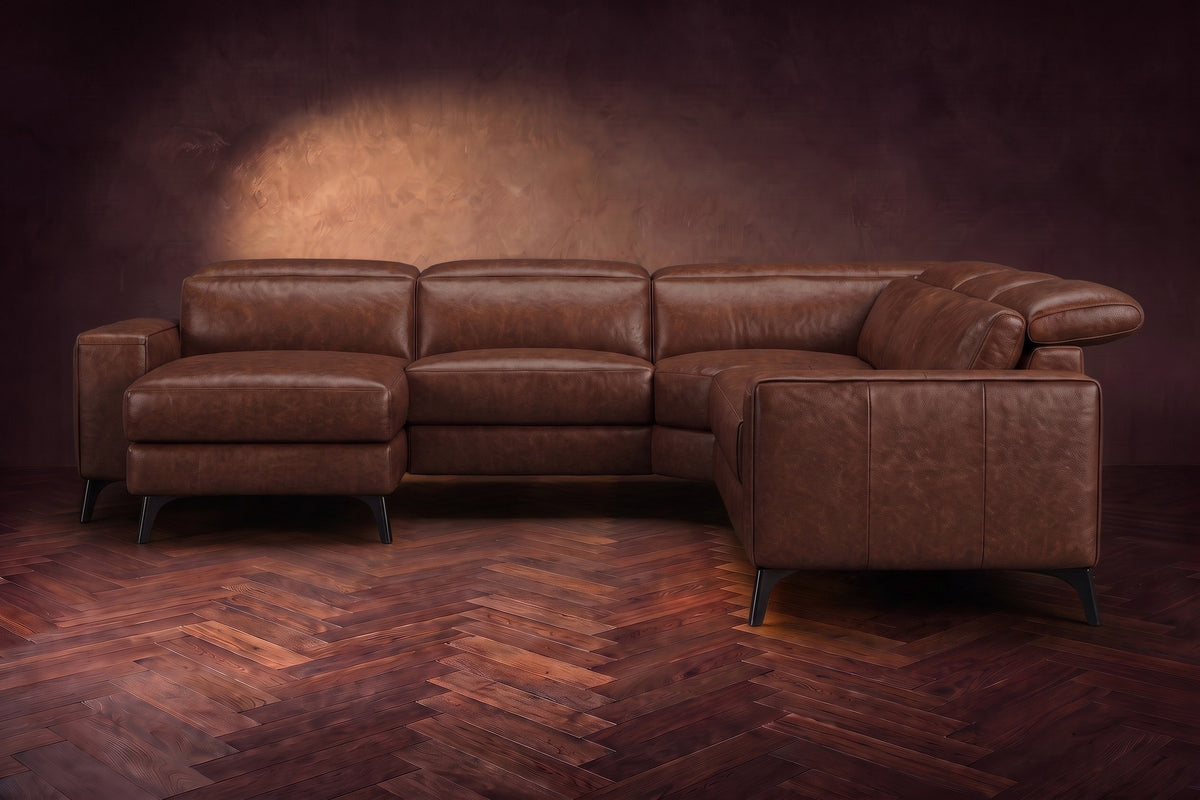 The Esther sectional seen from the front in Burnished Chestnut distressed full leather on a dark herringbone floor, the chaise facing the camera and the footrest closed. Shown in Burnished Chestnut, Left chaise.