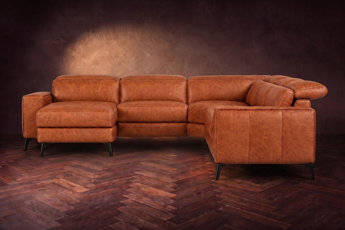 The Esther sectional seen from the front in Tuscan Cognac distressed full leather on a dark herringbone floor, the chaise facing the camera and the footrest closed. Shown in Tuscan Cognac, Left chaise.