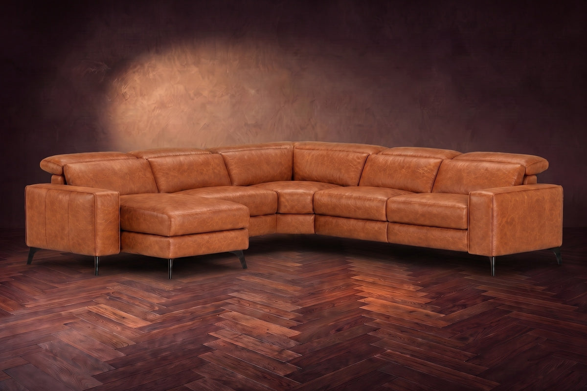 The Esther sectional in Tuscan Cognac distressed full leather on a dark herringbone floor, headrests down and footrest closed. Shown in Tuscan Cognac, Left chaise.