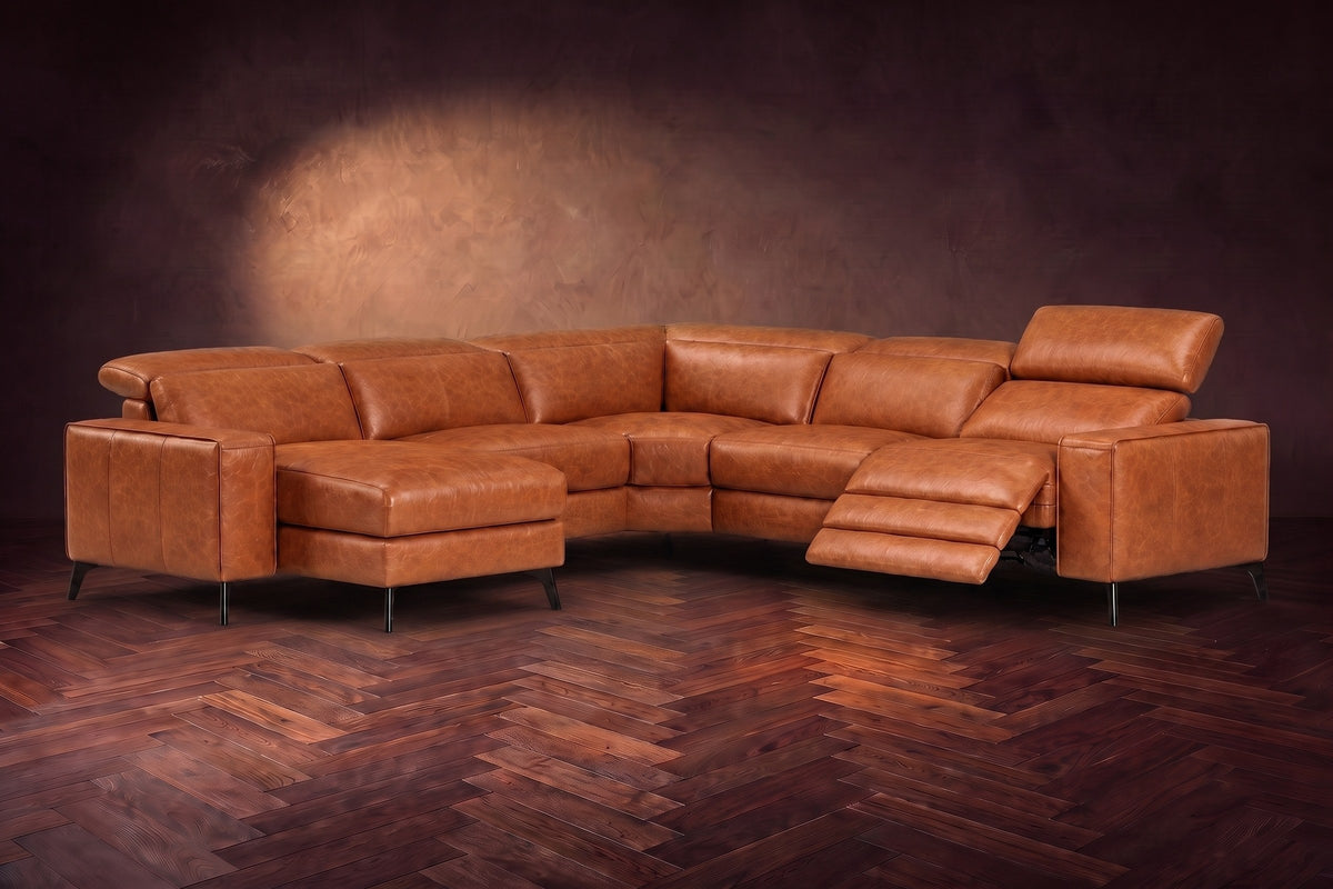 The Esther sectional in Tuscan Cognac distressed full leather on a dark herringbone floor, the power recliner at the arm end open with its one-piece footrest out and its headrest raised. Shown in Tuscan Cognac, Left chaise.