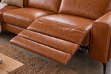 The open Esther recliner in Tuscan Cognac beside its box arm, the one-piece footrest out in three padded stages over a jute rug, a cushion and a knit throw on the far seat. Shown in Tuscan Cognac, Left chaise.