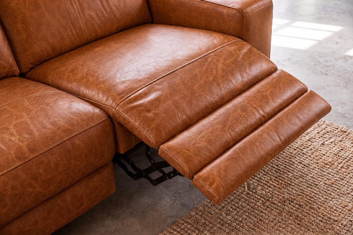 Looking down on the open Esther recliner in Tuscan Cognac: the one-piece footrest out in three padded stages, the black linkage beneath and the seat beside it closed. Shown in Tuscan Cognac, Left chaise.