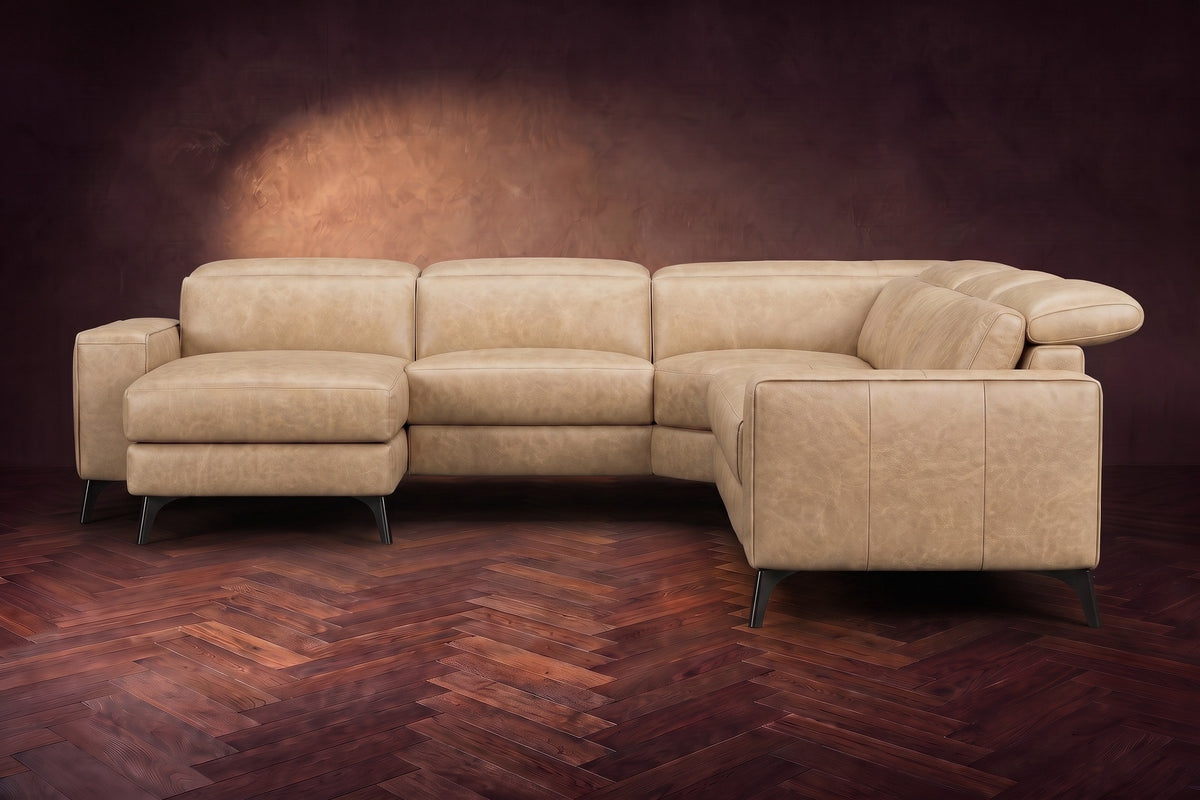 The Esther sectional seen from the front in Washed Sand distressed full leather on a dark herringbone floor, the chaise facing the camera and the footrest closed. Shown in Washed Sand, Left chaise.