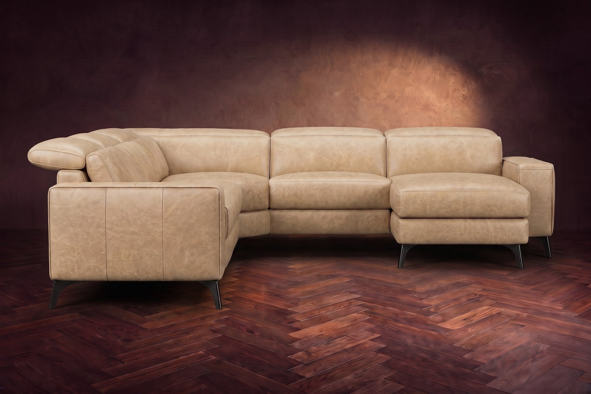 The Esther sectional seen from the front in Washed Sand distressed full leather on a dark herringbone floor, the chaise facing the camera and the footrest closed. Shown in Washed Sand, Right chaise.