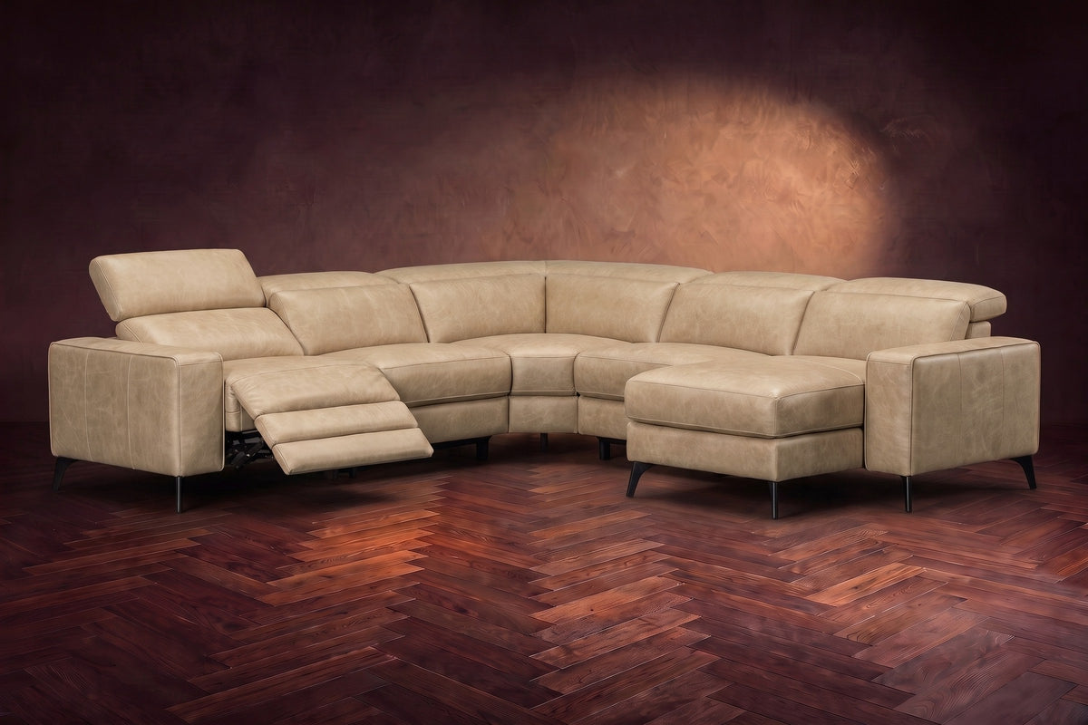 The Esther sectional in Washed Sand distressed full leather on a dark herringbone floor, the power recliner at the arm end open with its one-piece footrest out and its headrest raised. Shown in Washed Sand, Right chaise.