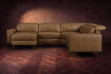 The Esther sectional seen from the front in Weathered Saddle distressed full leather on a dark herringbone floor, the chaise facing the camera and the footrest closed. Shown in Weathered Saddle, Left chaise.
