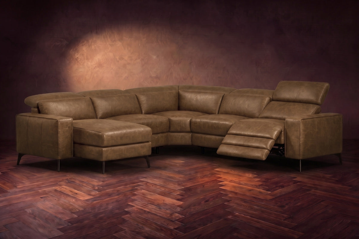 The Esther sectional in Weathered Saddle distressed full leather on a dark herringbone floor, the power recliner at the arm end open with its one-piece footrest out and its headrest raised. Shown in Weathered Saddle, Left chaise.
