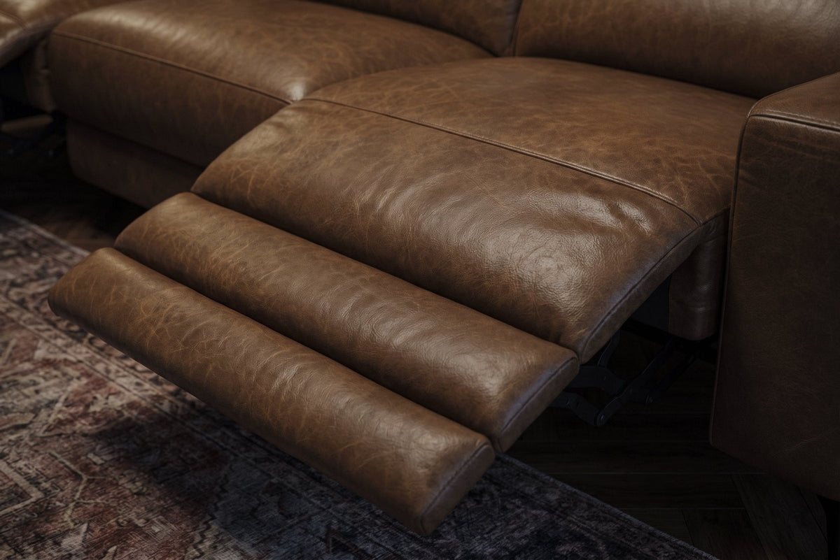 The open Esther recliner in Weathered Saddle, its one-piece footrest out in three padded stages over a patterned rug. Shown in Weathered Saddle, Left chaise.