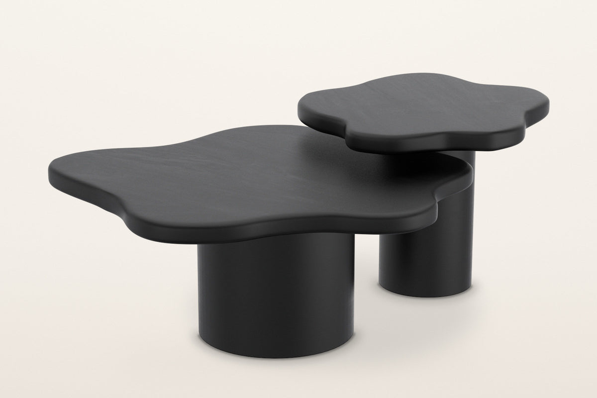 Exilles cloud-shaped coffee tables in black, set of two: a large low table and a smaller, taller one on round drum bases, on a warm white studio backdrop