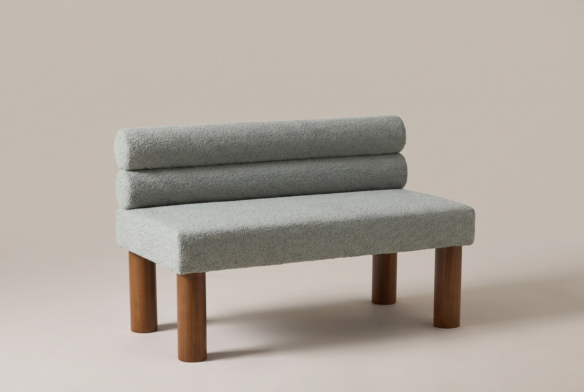 Fabriano armless bench in sage boucle with two stacked bolsters and four round walnut-stained legs