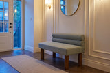 Fabriano bench in a panelled townhouse front hall at dusk, under a lit brass sconce and a round mirror