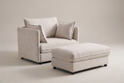 Faenza chair-and-a-half in beige chenille with its storage ottoman, three-quarter view on a warm grey studio backdrop