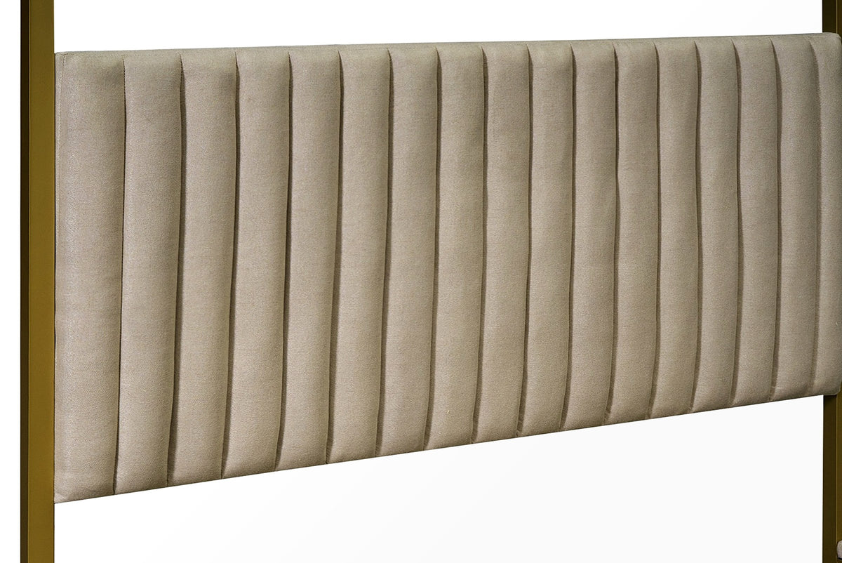 Close-up of the channelled beige headboard held between two gold posts