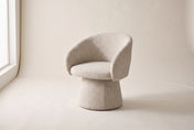 Finley accent chair in Sand, three-quarter view on a warm off-white studio backdrop: a curved barrel back wrapping into low