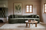The Fiora sofa in Green in a timber house in the Black Forest with spruce board walls and a tiled stove