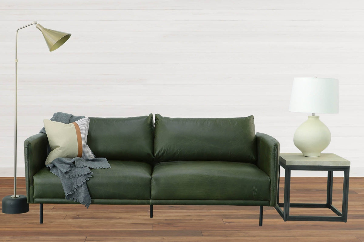 Florence ceramic lamp on a black metal side table beside a green leather sofa