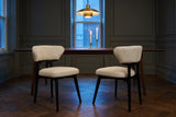 Two Fosdinovo dining chairs in front of a walnut table in a panelled Toronto dining room at dusk under a brass pendant lamp