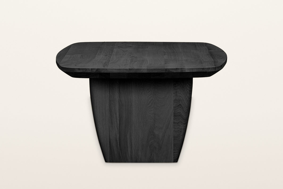 Frontino coffee table in Black from the end on a warm white studio backdrop: the slab leg narrowing toward the floor