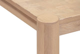 Close-up of a Furore corner in Biscotti Oak: the round column top flush in the curved corner, the apron set back