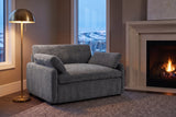 Gallipoli chair in charcoal gray in a Calgary family room at dusk, beside a limestone fireplace and a lit brass floor lamp