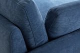 Close-up of the ribbed denim blue chenille where the arm, the back cushion and a pillow meet, with their top-stitched edges