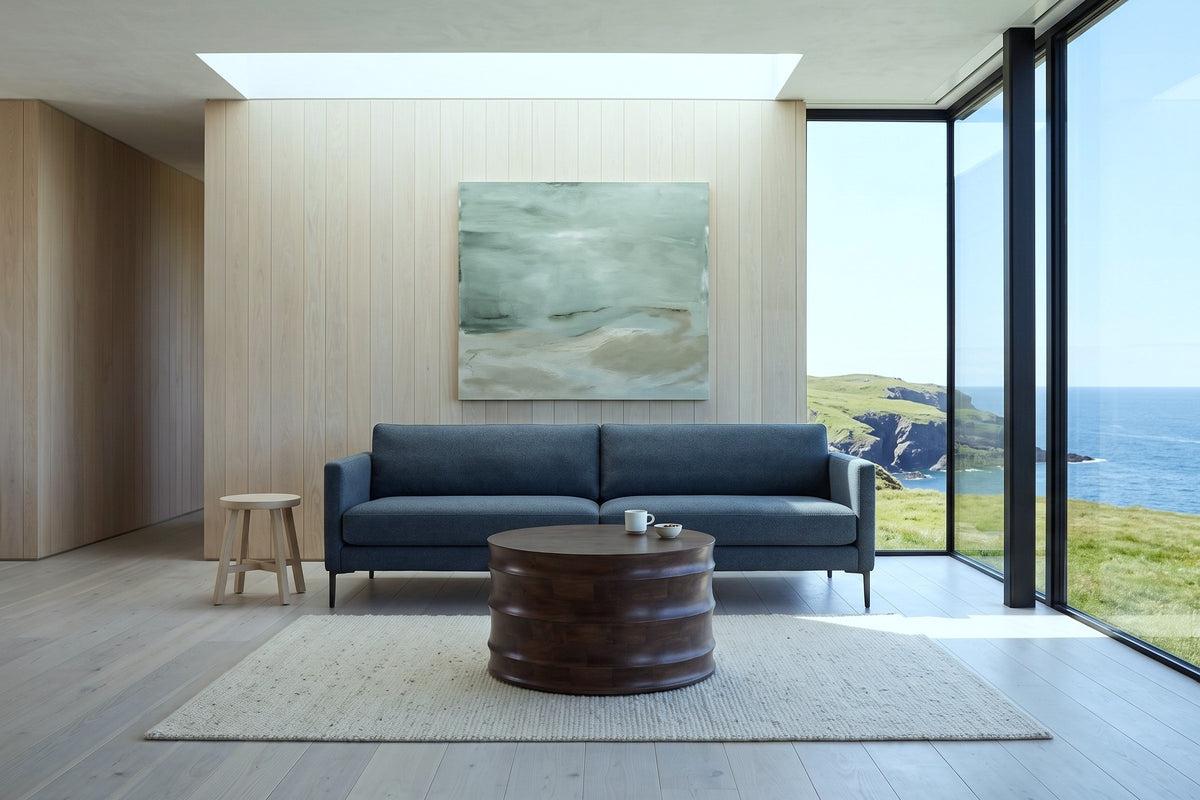 Gangi coffee table in Walnut facing the camera before a small blue-grey sofa in a Bonavista clifftop house