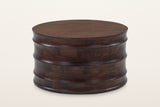 Gangi round mango coffee table in Walnut, raised three-quarter view on a warm white studio backdrop: a flat top over four cur
