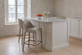 Two Gavi counter stools in beige at a white marble kitchen island in an old stone house in Quebec City