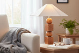 Geneva wood table lamp on an end table beside a cream sofa and knit throw