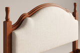 Close-up of the Gradara headboard: two turned finials, the moulded wood crest and the beige linen-look panel