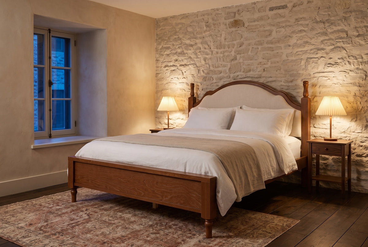Gradara bed against a pale limestone wall at dusk, with pleated lamps lit on two walnut nightstands