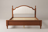 Gradara bed in brown, straight front view: arched upholstered headboard between two turned finial posts