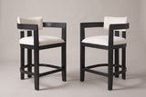 Gradisca counter stools, set of 2, in Black with ivory boucle, angled toward each other on a warm grey studio backdrop