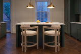 Two Gradisca counter stools in Natural Ash at a marble island under brass pendants in a Toronto townhouse kitchen at dusk