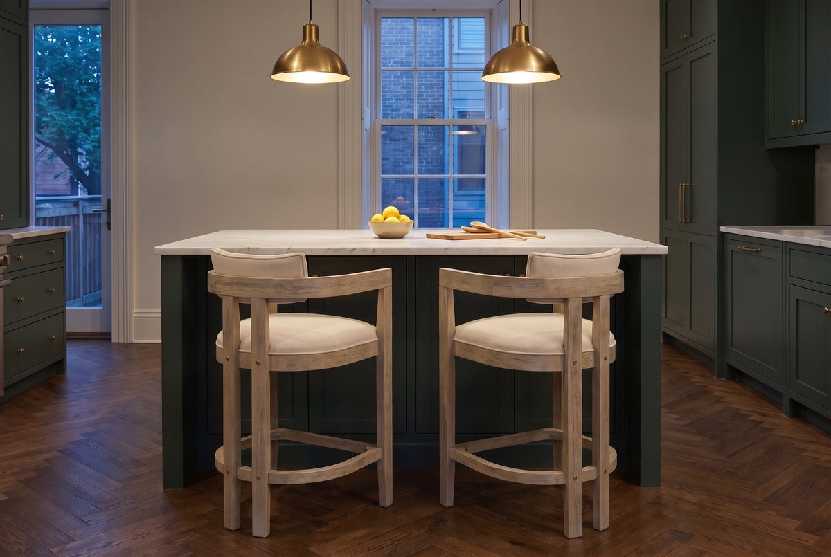Two Gradisca counter stools in Natural Ash at a marble island under brass pendants in a Toronto townhouse kitchen at dusk