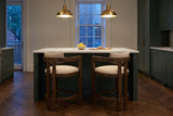 Two Gradisca counter stools at a marble island under brass pendants in a Toronto townhouse kitchen at dusk