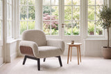 Grado chair in oat in a bright Victoria garden room with tall paned windows, a pale oak side table and an olive tree