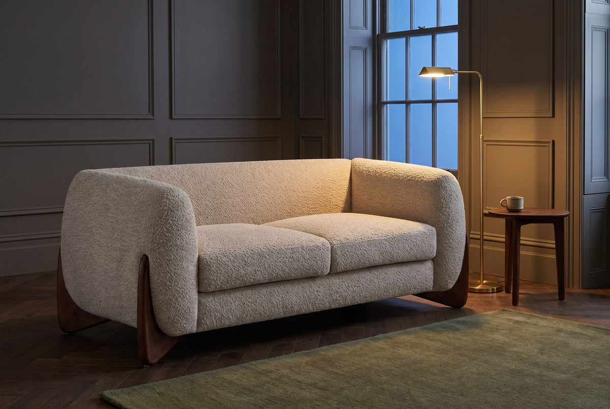 Greccio boucle loveseat in a dark panelled townhouse sitting room at dusk, a brass floor lamp lit beside it